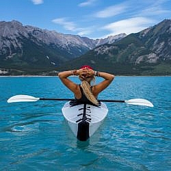 Woman kayaking along a mountainous shoreline